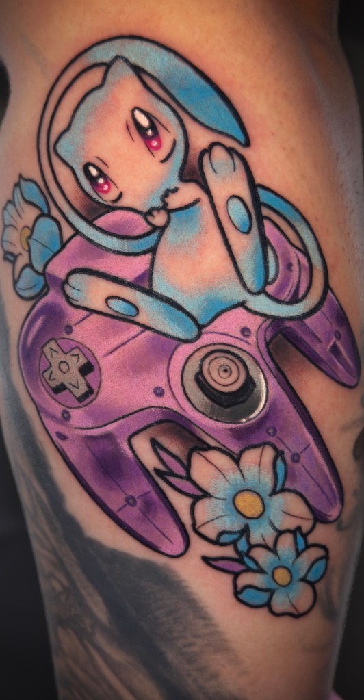 Neo traditional shiny Mew tattoo coming out of a purple Nintendo 64 controller by Kara Noel at Folklore Tattoo Co. in Dallas